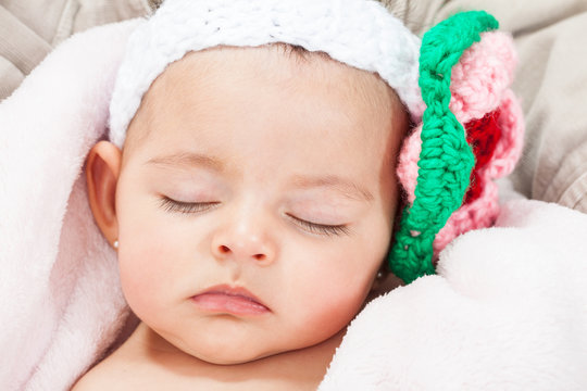 Hermosa bebita durmiendo con una banda adornada con una flor tejida