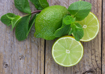 Juicy ripe limes and mint on wooden table - 81072269