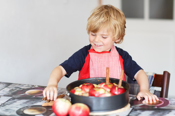Adorable little boy helping and baking apple pie in home''s kitc