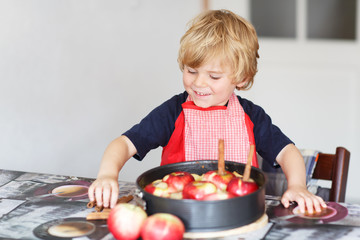 Adorable little boy helping and baking apple pie in home''s kitc
