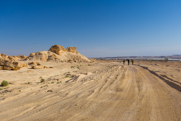 Fototapeta na wymiar Backpackers walking desert road.