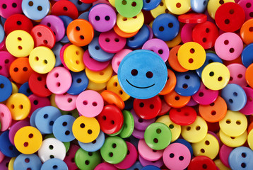 Fototapeta na wymiar Colorful buttons pile multicolor only one is smiling