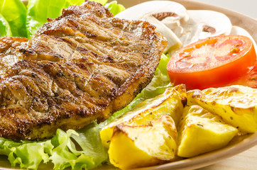 Grilled meat dish with tomato, potatoes and mushrooms