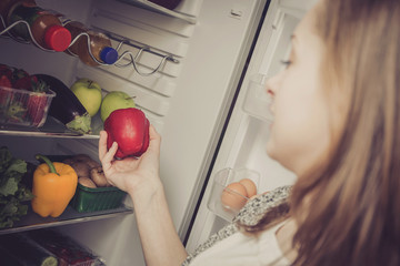 Junge Frau nimmt Obst und Gem&uuml;se aus dem K&uuml;hlschrank raus