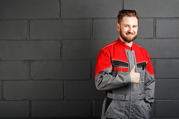 Fototapeta na wymiar portriat of smiling man wearing overalls near brick wall