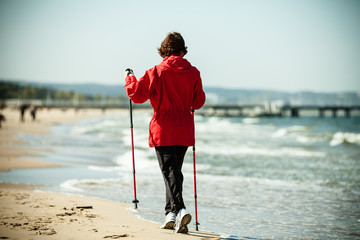 Nordic walking. Woman hiking on the beach.