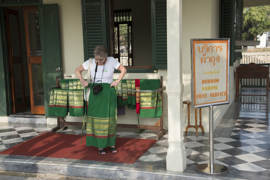 Tourist borrows a sarong before entering a Thai temple