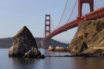 Tuinposter Old lighthouse and fog station under Golden Gate bridge in sunri © elgad