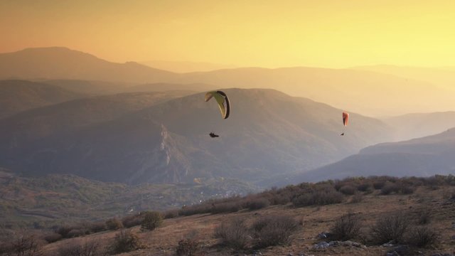 Paraglider Soaring Over The Mountains during sunset
