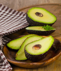 Fresh avocados on  wooden cutting board .