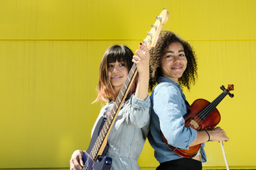 Women musicians standing back to back with instruments