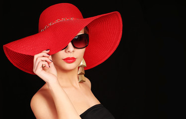 Woman in red hat and sunglasses over black background