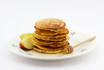 Stack of pancakes with apple slices and honey on the plate 