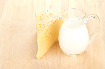 Big piece of cheese, glass jug with milk