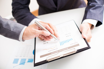 Two businessmen looking at report and having a discussion in off