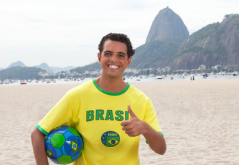 Brasilianischer Fan mit Ball vor dem Zuckerhut zeigt Daumen