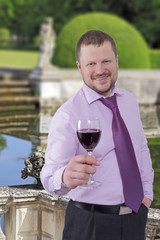 Businessman holding glass of wine with beautiful park in