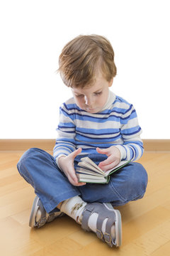 Boy reading book seating on the floor on white background