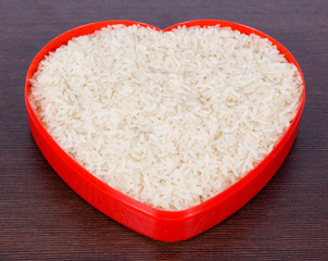 Uncooked parboiled rice in a red heart plate