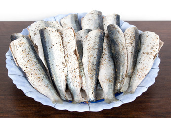 Sprats with salt and pepper ready for cooking on a plate