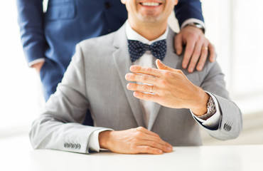 close up of male gay couple with wedding rings on