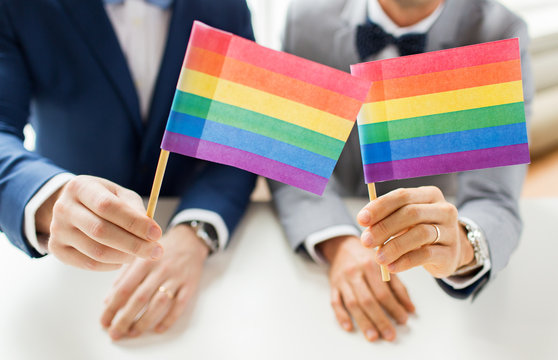 Close Up Of Male Gay Couple Holding Rainbow Flags