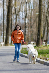 A little beautiful girl with her pet dog outdoors in park