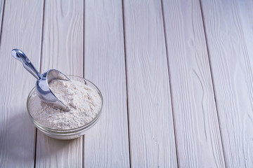 bowl with flour and scoop on white painted old wooden board food