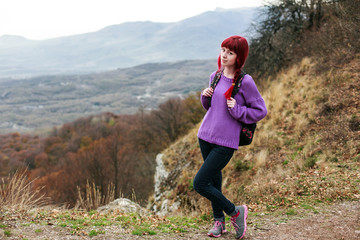 girl with red hair and a backpack on a mountain