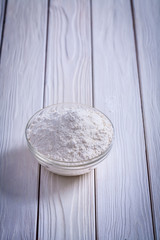 natural flour in glass bowl on white painted old wooden board fo