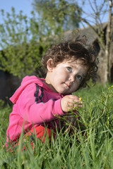 In summer, the garden sits a little curly girl and sees a yellow