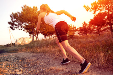 Young woman jogger running on the road in morning park