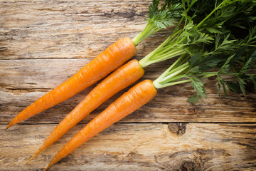 Fresh carrots on the wooden background.