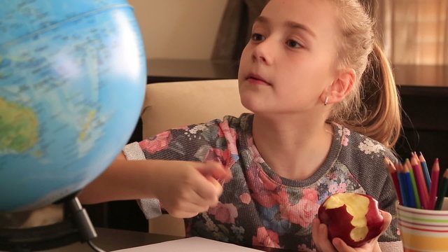 Little girl study at home and eating apple