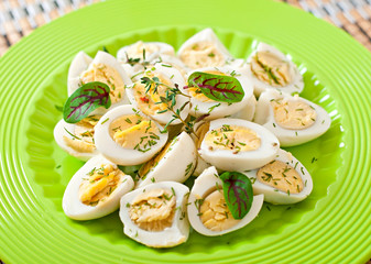 Boiled quail eggs halves on a green plate