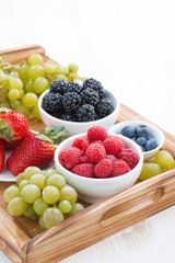 wooden tray with fresh berries and grapes, vertical