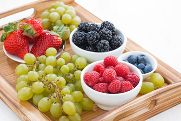 wooden tray with fresh berries and grapes