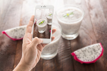 Taking photo of dragon fruit smoothie on wooden table