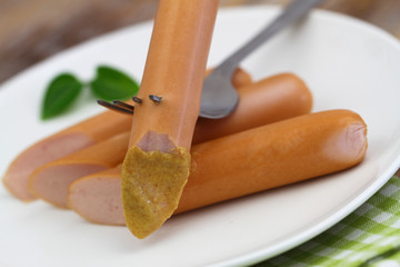 Frankfurter with mustard on fork, closeup