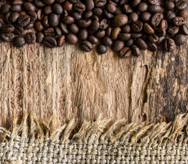 Coffee beans and hemp sack on wooden background.