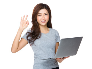 Young woman with notebook computer and ok sign