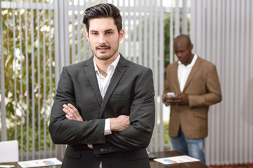 Cheerful young businessman in formalwear keeping arms crossed