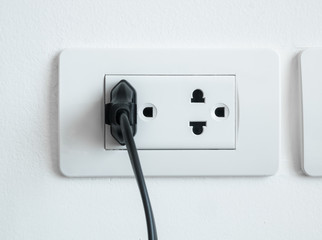 electronic power plug plugged in a wall socket