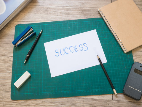 Stationery and hand writing success text paper on cutting mat