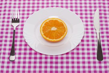 orange fruit in a white ceramic plate with the fork and knife