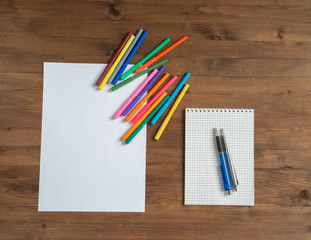 multicolor markers, paper sheet and notebook