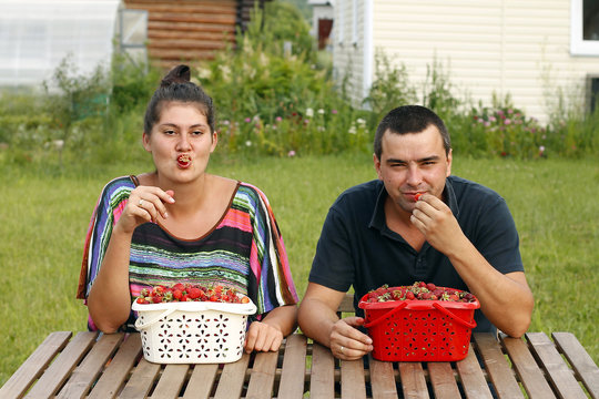 Happy man and woman eating strawberry