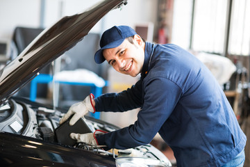Auto mechanic putting oil in a car engine