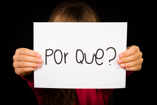 Child holding sign with Portuguese word Por Que - Why