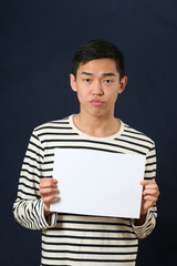 Young Asian man showing white copy space page and looking at cam